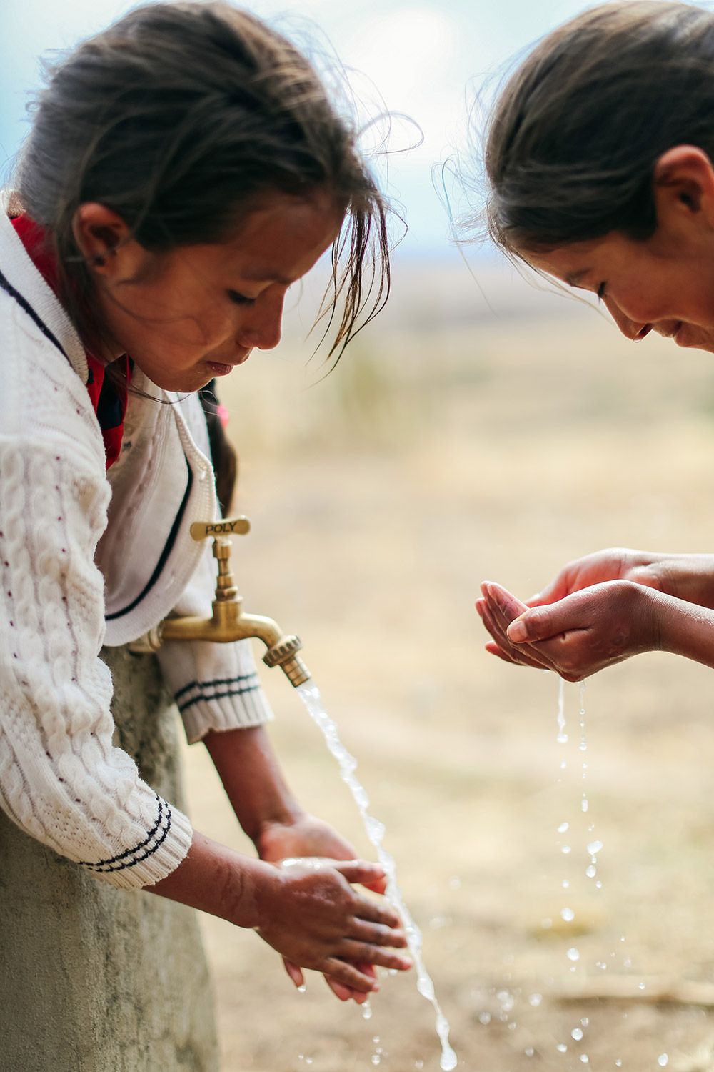 two girls washing their hands outside at a faucet | Clean Water in Bolivia | Where We Work | Water For People