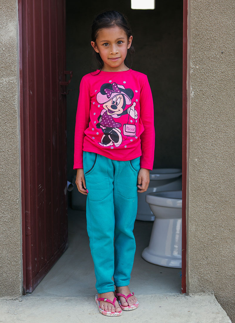 little girl standing in front of a bathroom