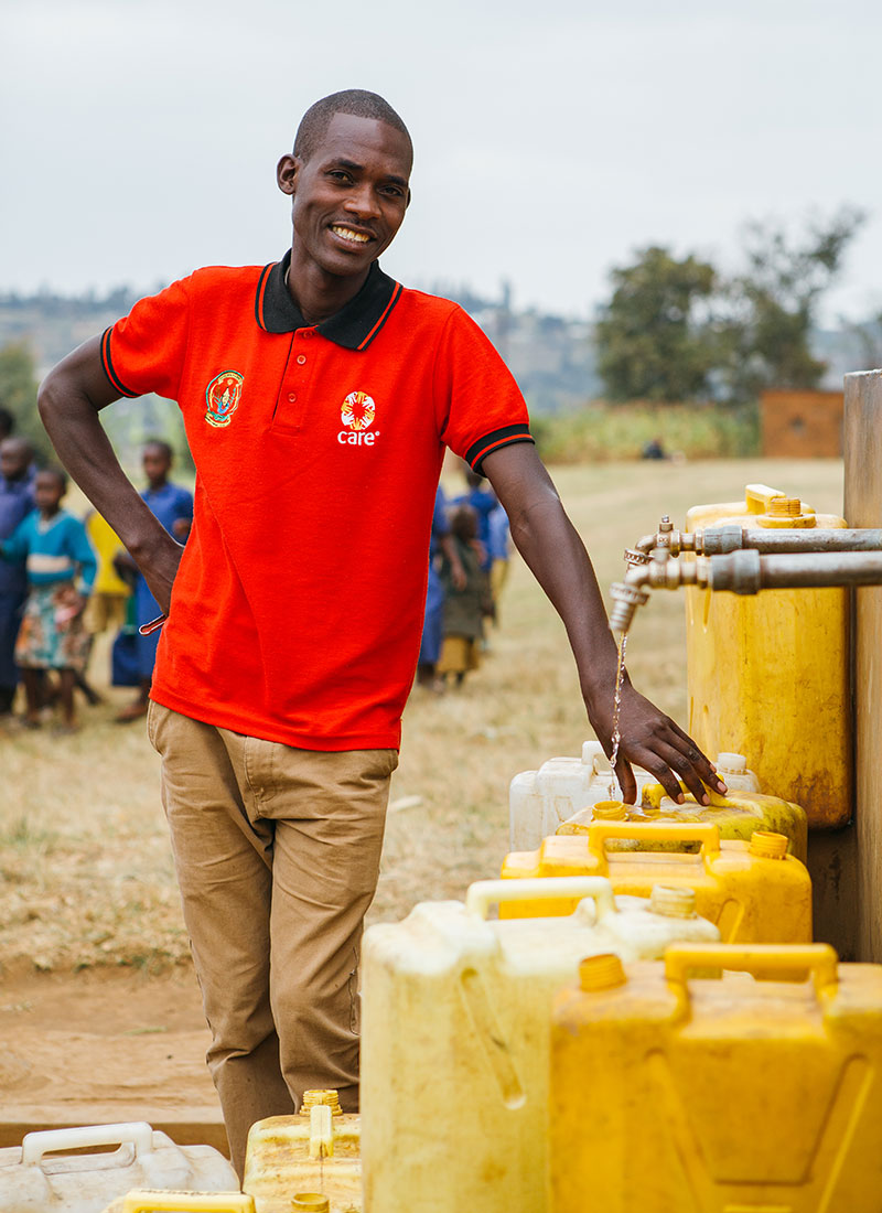 man filling up yellow jugs with water at outdoor faucet