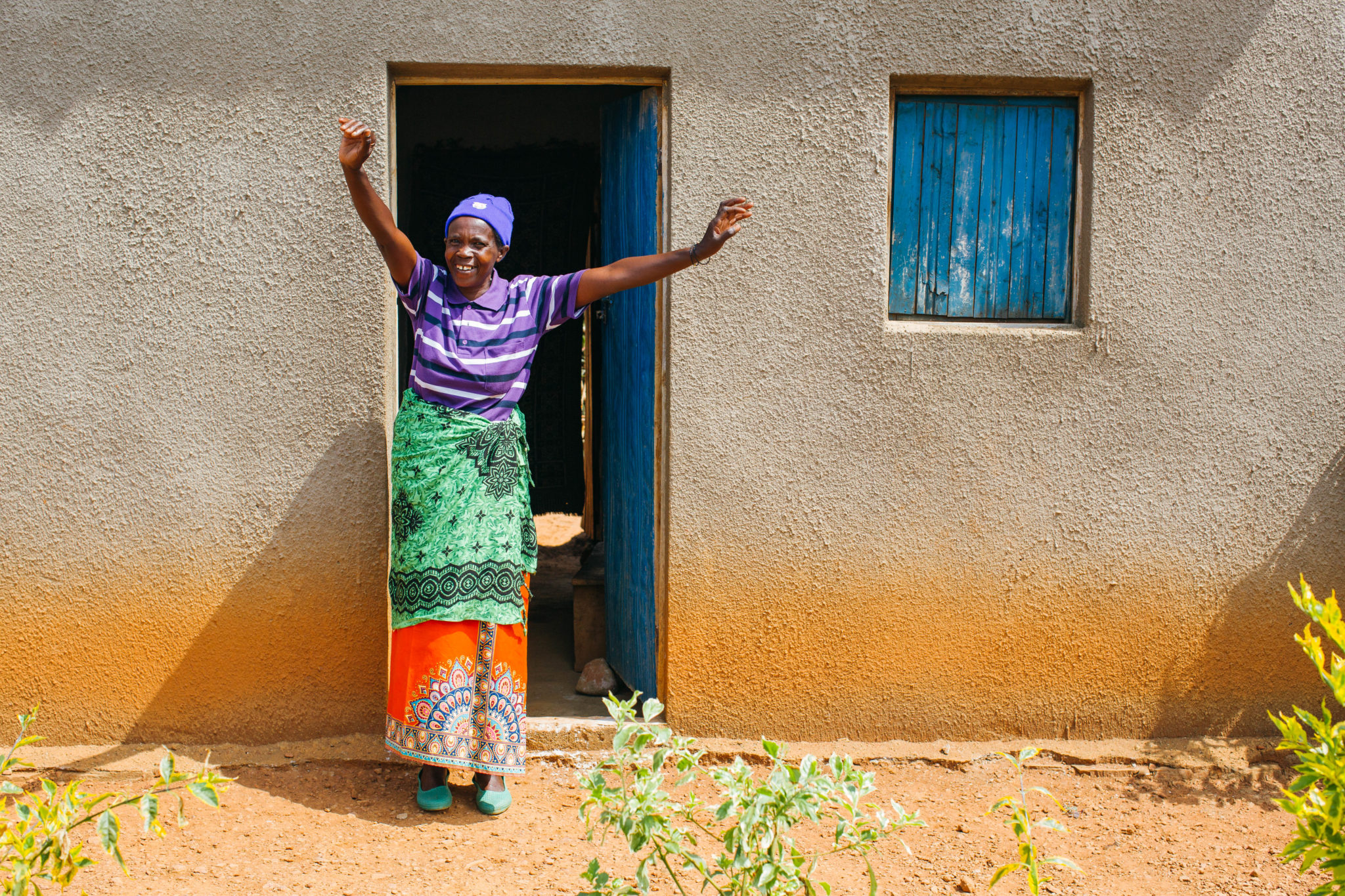 Didacienne stands outside the home she built with the income she earned as a water seller. 
