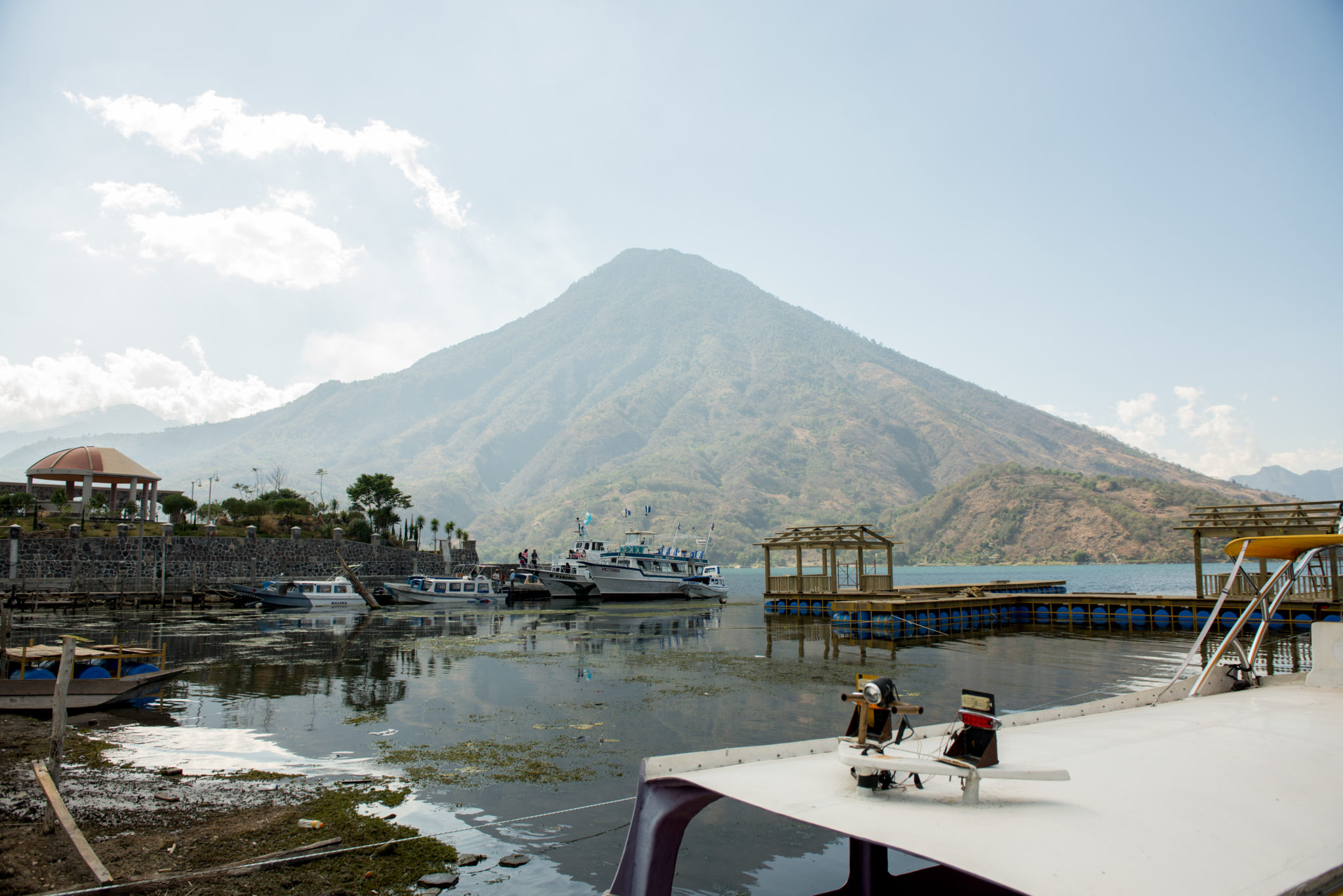 Guatemala-LakeAtitlan-201703-43 Photograph of a body of water, boats, and a mountain in the distance.