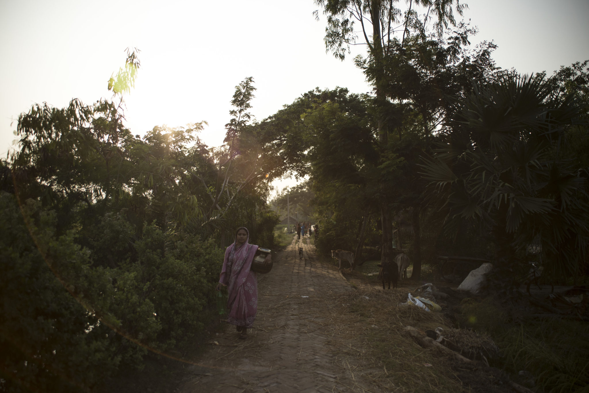 photograph of a woman walking at dusk down a dirt road