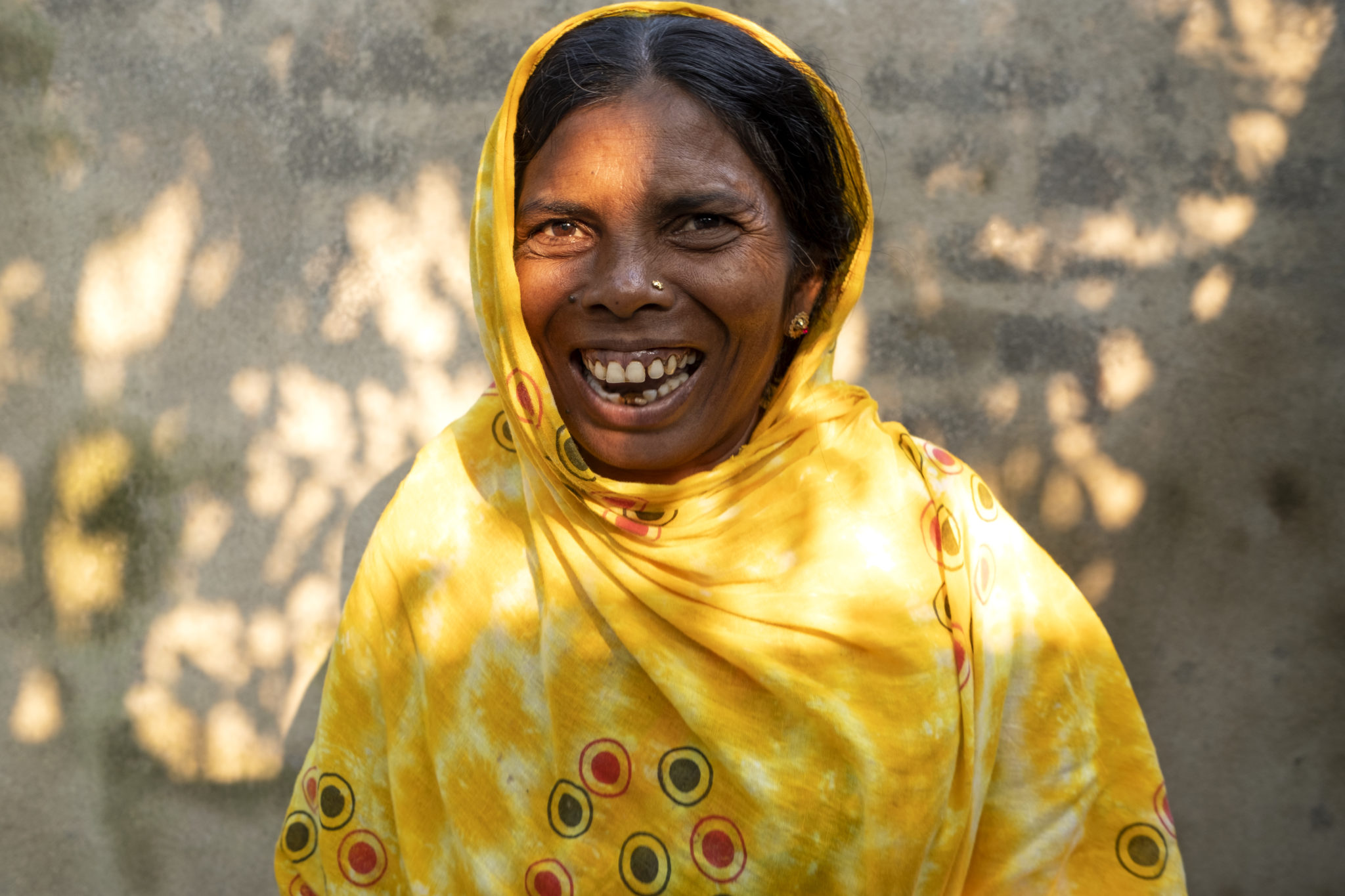 photograph of a woman in a yellow sari smiling
