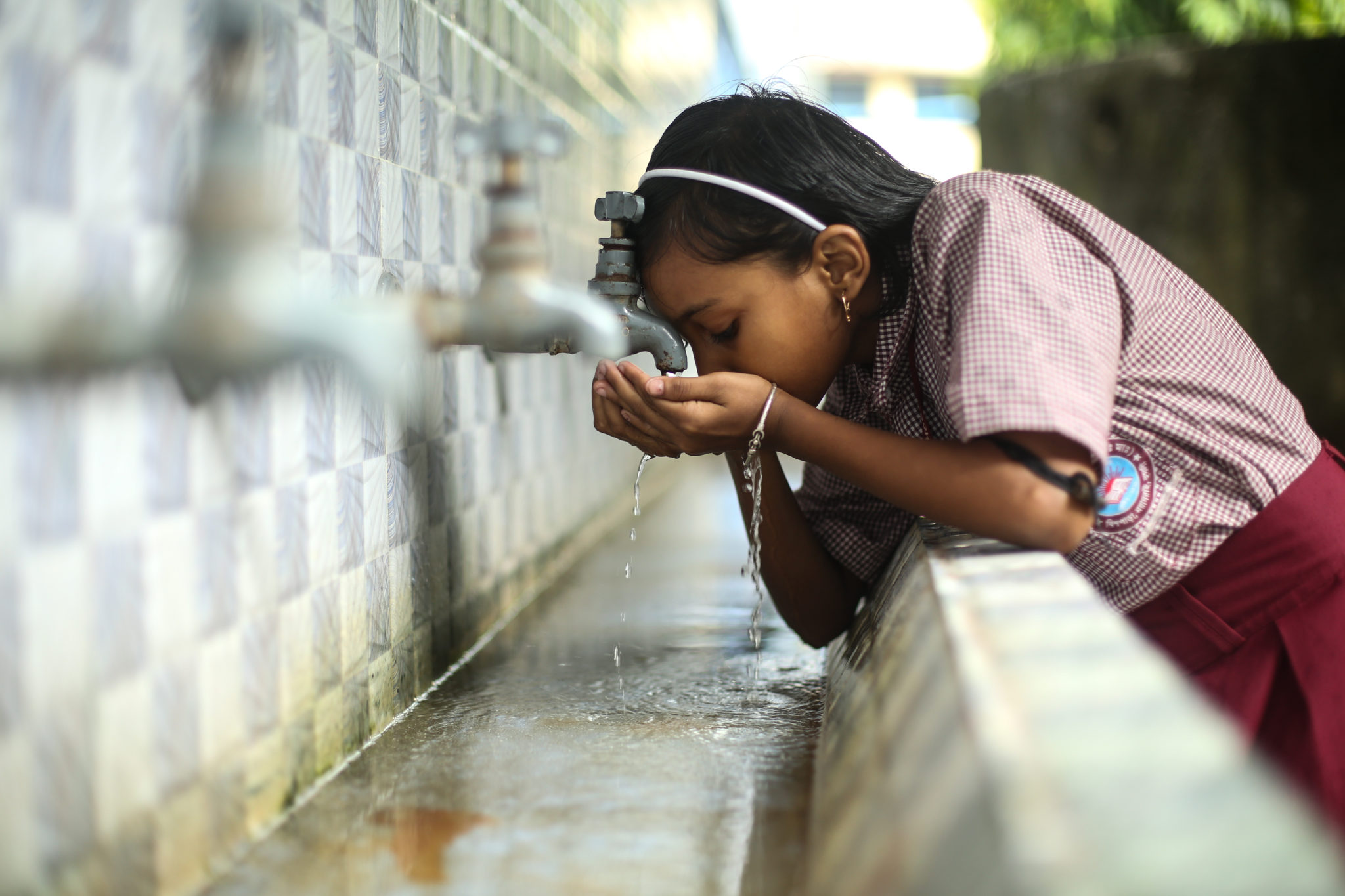 Photograph of a child drinking water from a tap