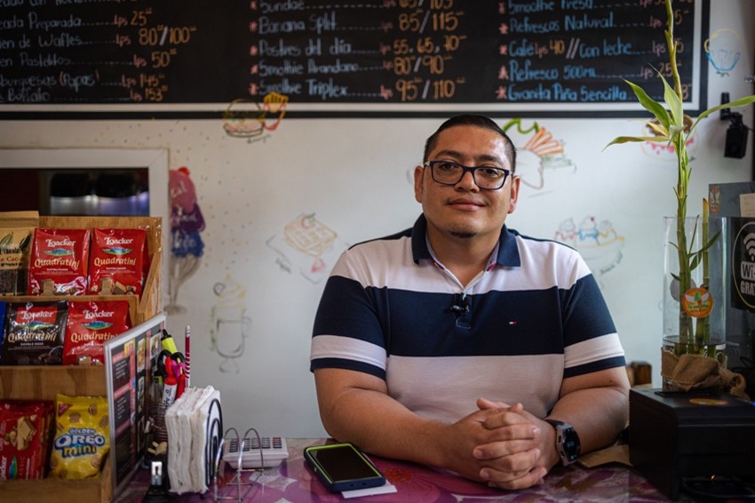 Photograph of a shop owner sitting with his merchandise