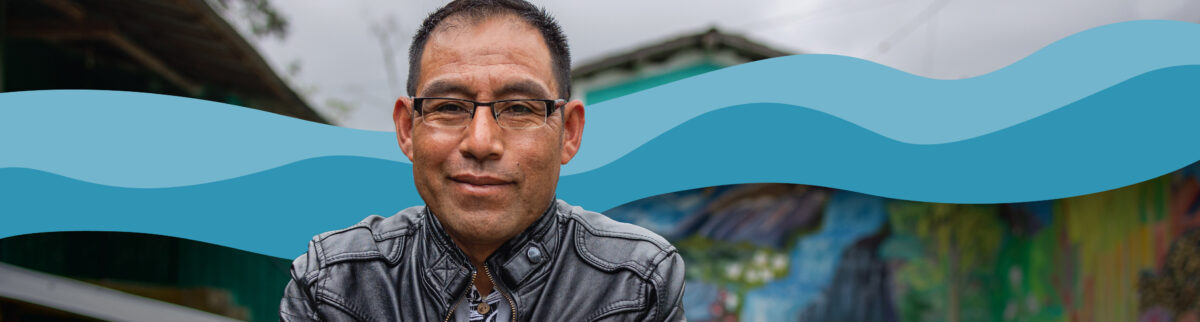 Photo of a man standing in front of a colorful mural with blue graphic waves