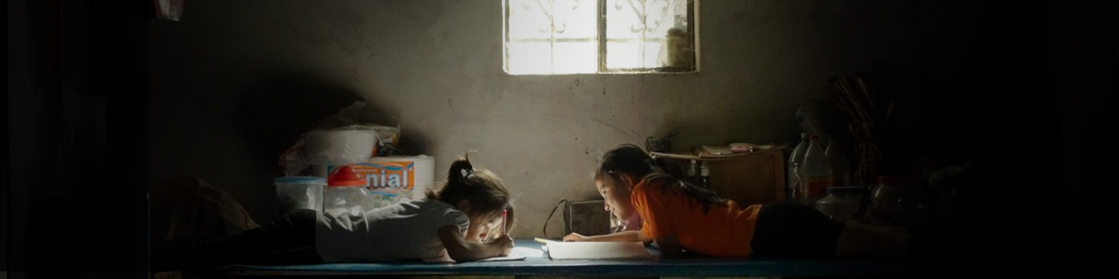 Two students doing homework in a dimly lit room.