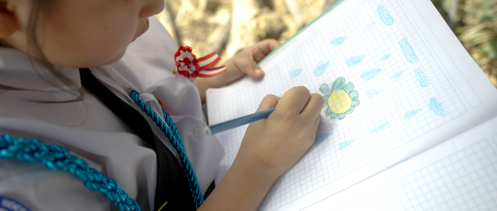 A student colouring a flower in her notebook