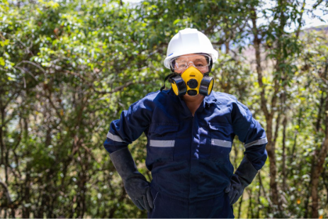 The woman stands outdoors in protective gear, including a hard hat and face mask, prepared to treat and monitor the community’s water system.