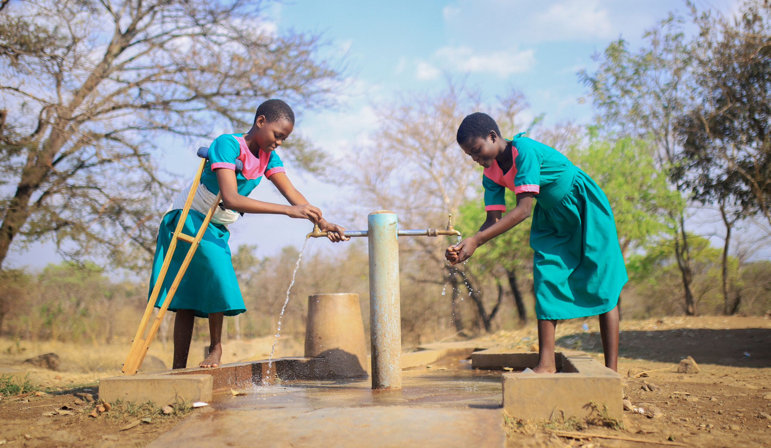 Grace and her friend collect water from their new school tap