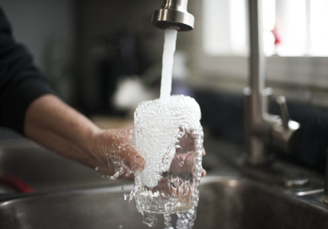 A McDowell County resident fills a glass of clean, running water made possible by DigDeep and McDowell County PSD