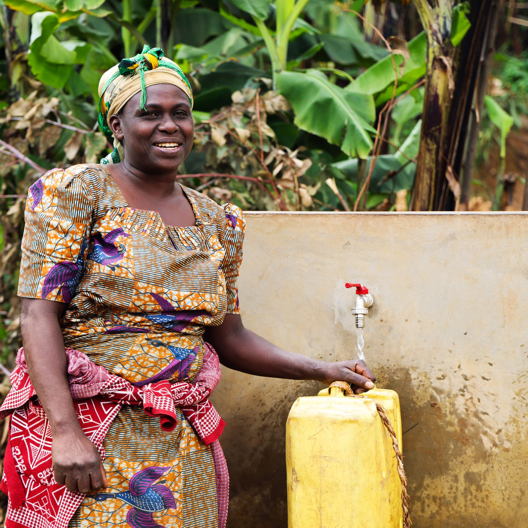 Immaculée stands in front of her community's new water point in Rwanda.