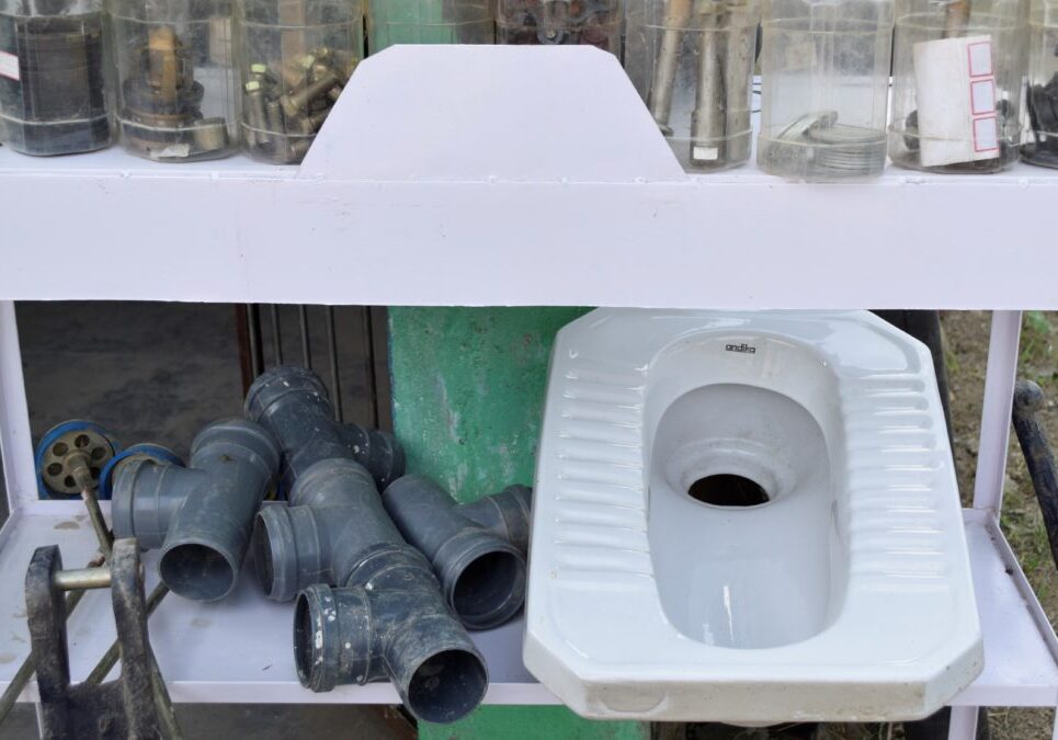 Photograph of toilet parts and pipes on a shelf
