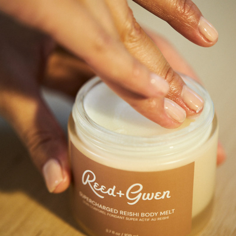 Photo of a hand reaching into a jar of cream from company Reed and Gwen