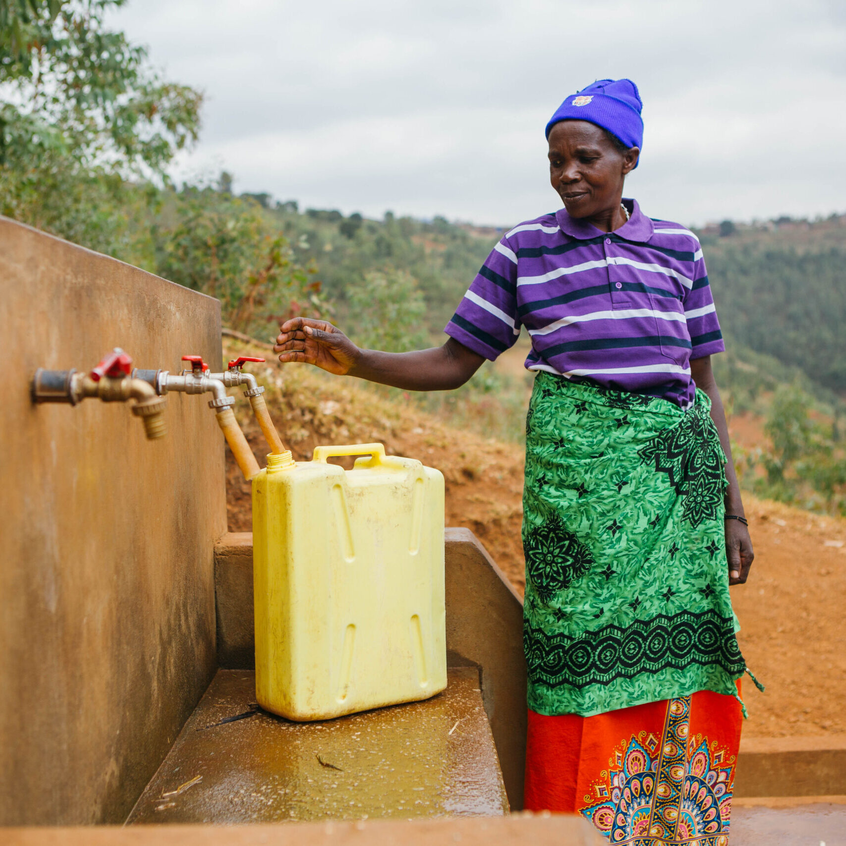 Didacienne collects water at the new tap next to her home. 