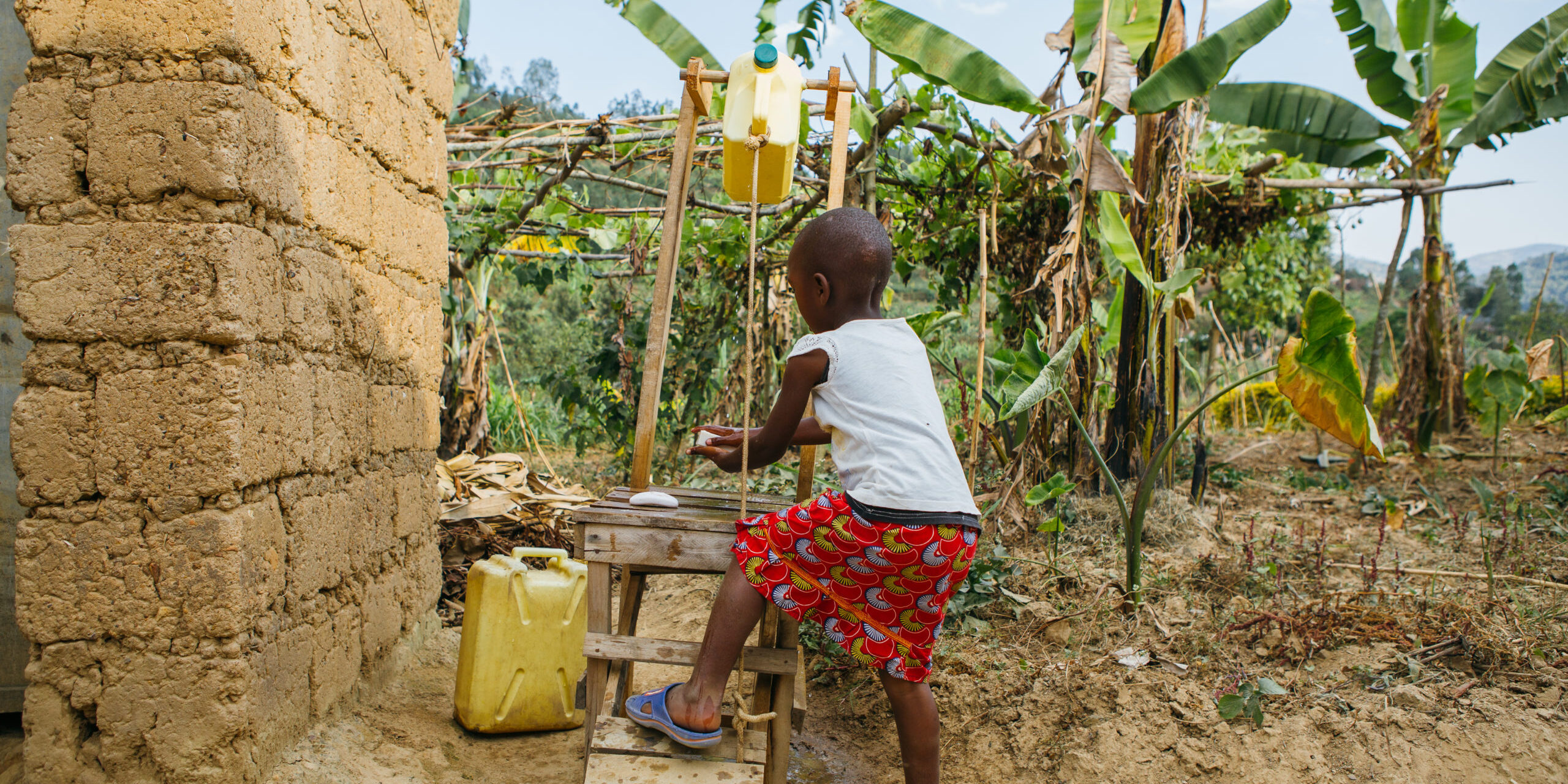 Photograph of a child using a tippy tap hygiene device