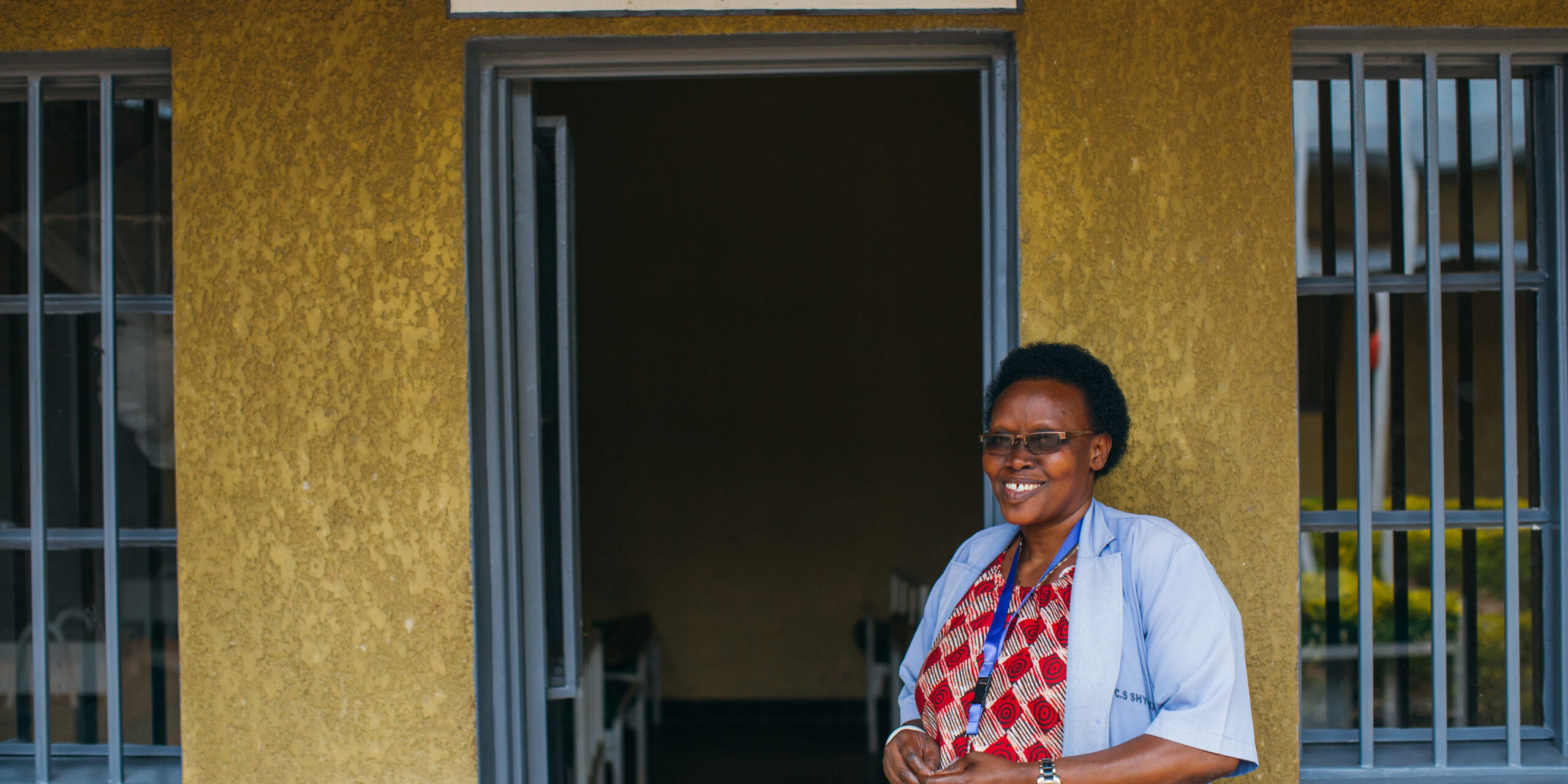 A nurse standing outside the entrance of a health center in Rulindo, Rwanda.