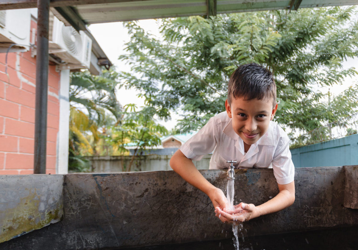 Student Luis stands with his school's improved safe water and dignified sanitation infrastructure in Honduras (1)