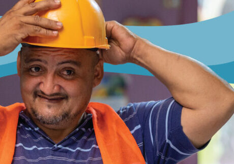 Photograph of a man putting on a safety helmet with graphic blue waves behind him