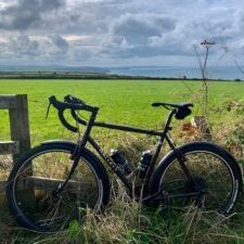 A bicycle leaned against a fence with a green field in the background